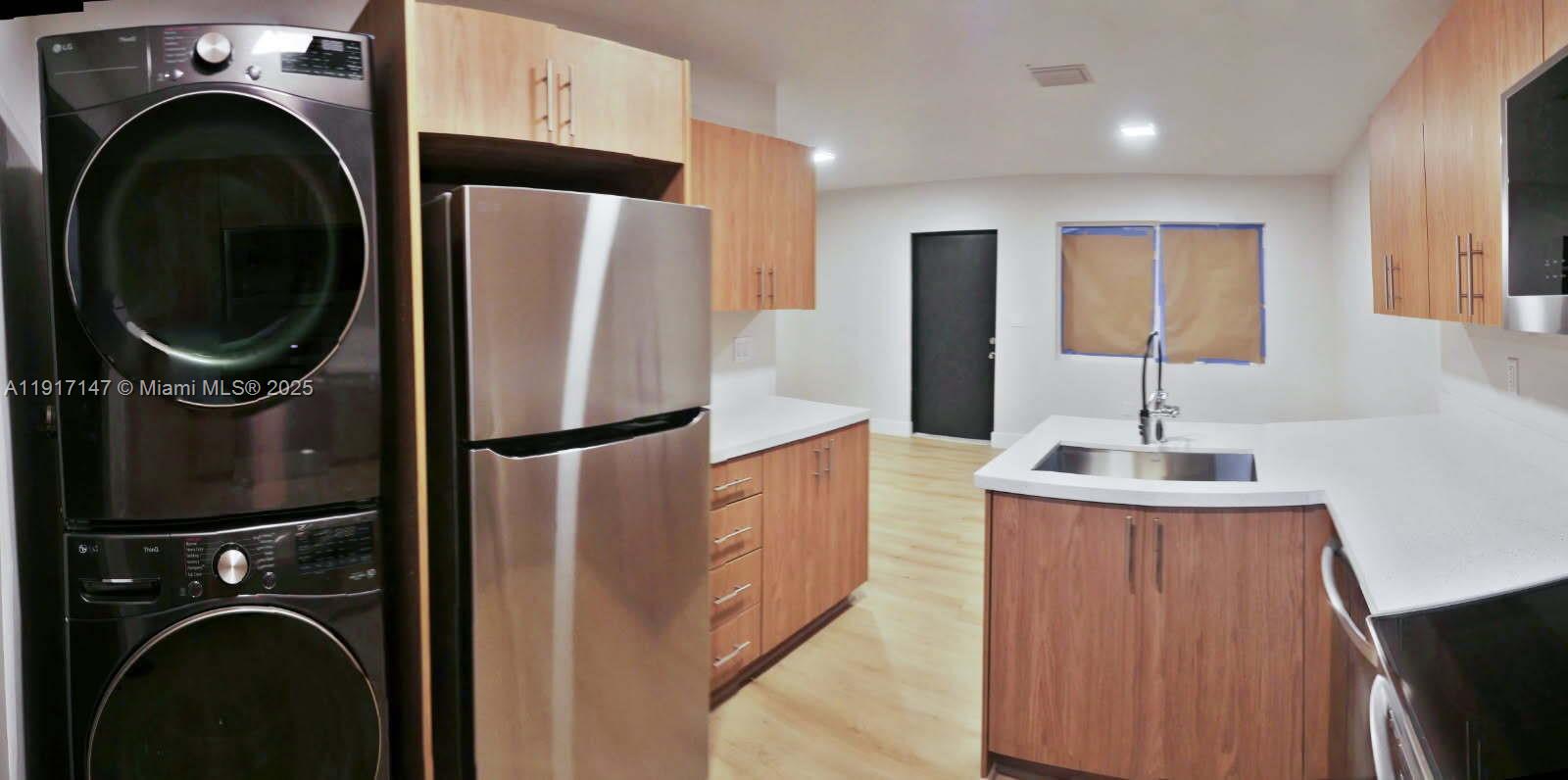 4557 Northwest 14th Avenue, Unit 4557 Miami, FL 33142 - Photo 2 of 13 a kitchen with refrigerator a washer and dryer
