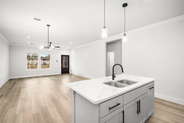 a kitchen with a sink a chandelier and wooden floor