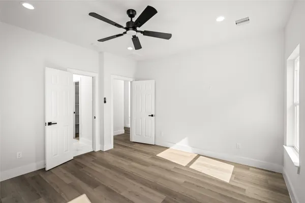 a view of empty room with wooden floor and fan