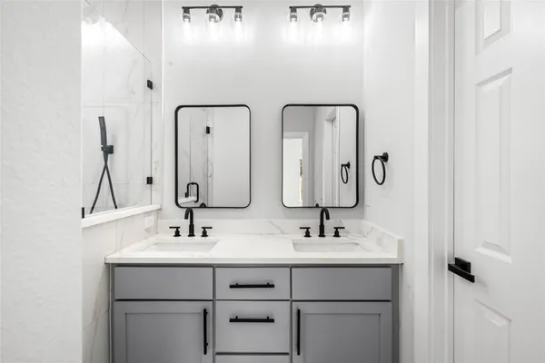 a bathroom with double vanity sink and two mirror