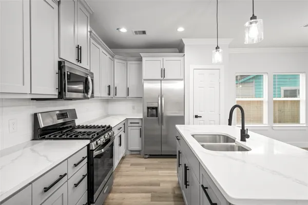 a kitchen with stainless steel appliances granite countertop a sink a stove a refrigerator cabinets and a kitchen island