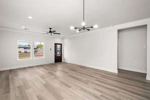 a view of an empty room with a window and wooden floor