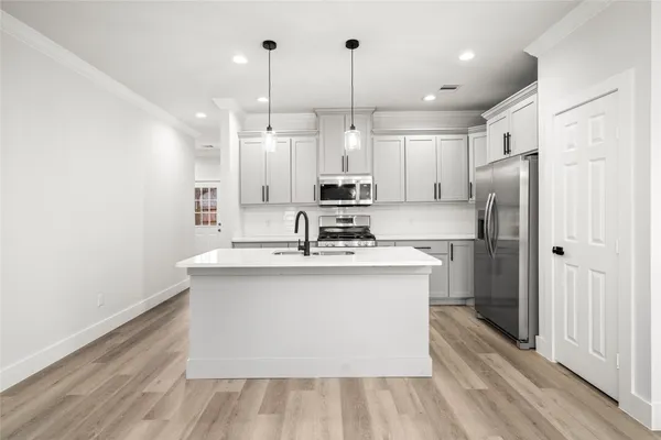 a kitchen with stainless steel appliances granite countertop a sink a stove a refrigerator and island with wooden floor