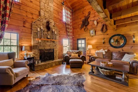 a living room with furniture a fireplace a rug and a large window