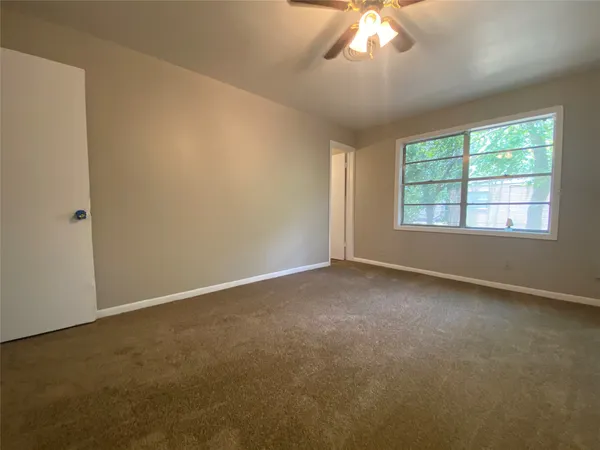 an empty room with a chandelier fan and windows