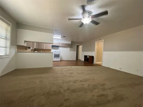 a view of a livingroom with a fireplace a ceiling fan and windows
