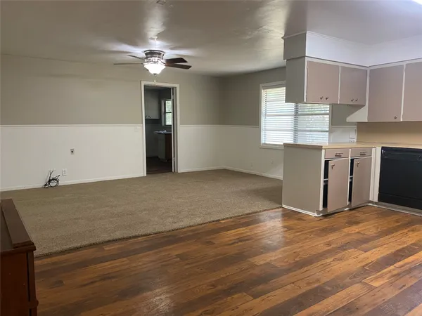a view of kitchen and empty room with wooden floor