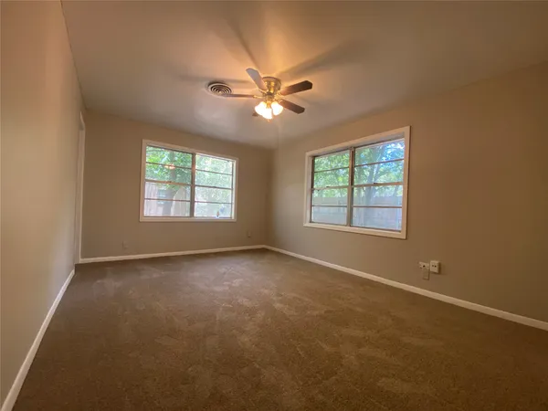a view of an empty room with window and chandelier fan
