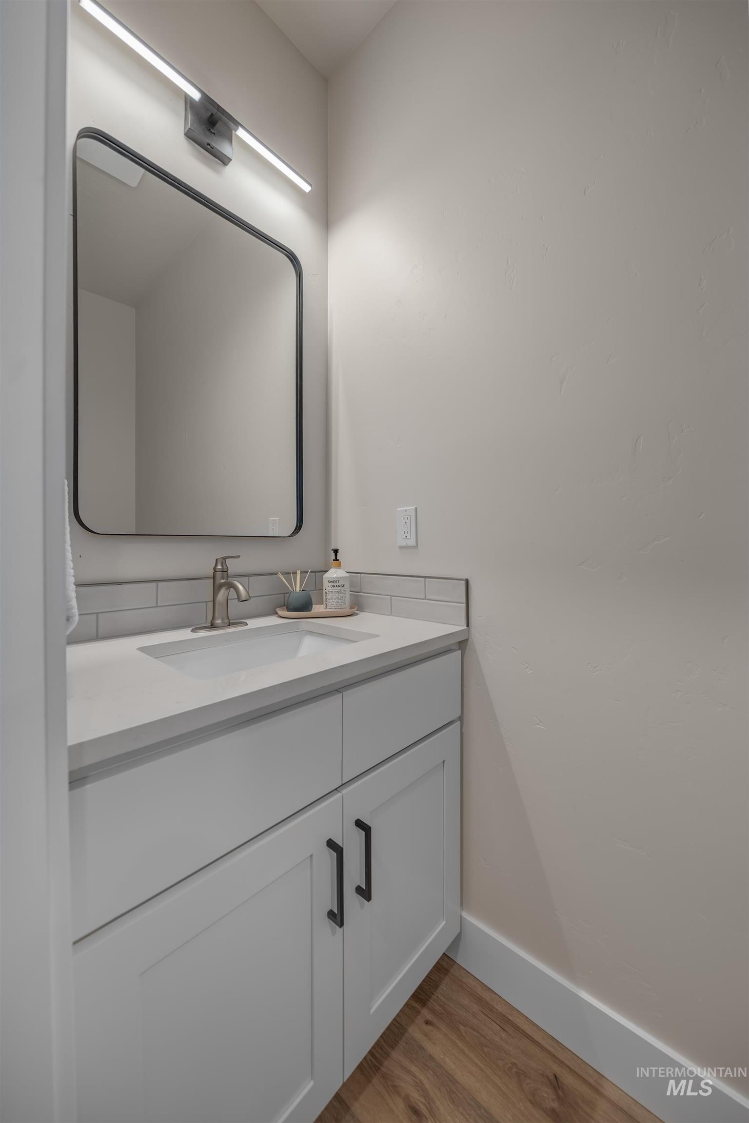 1371 Hansen Road Weiser, ID 83672 - Photo 29 of 44 Modern vanity with an integrated sink, brushed nickel faucet, light gray quartz-finish countertop, and subway tile backsplash