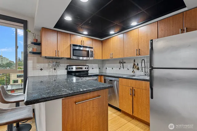 a kitchen with stainless steel appliances granite countertop a sink stove refrigerator and microwave