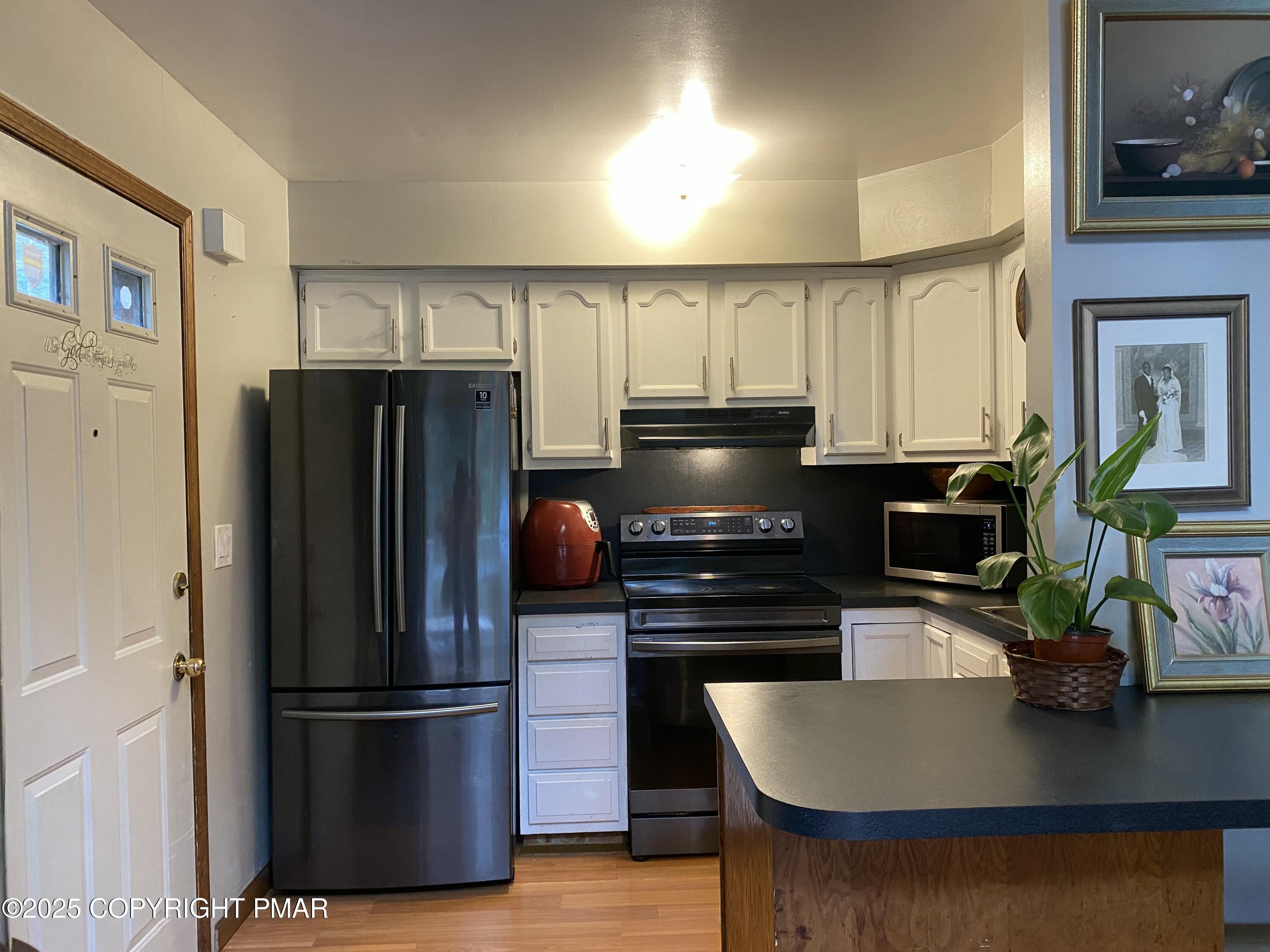 6119 Decker Road Bushkill, PA 18324 - Photo 5 of 8 a kitchen with kitchen island a stove a refrigerator and a sink with wooden floor