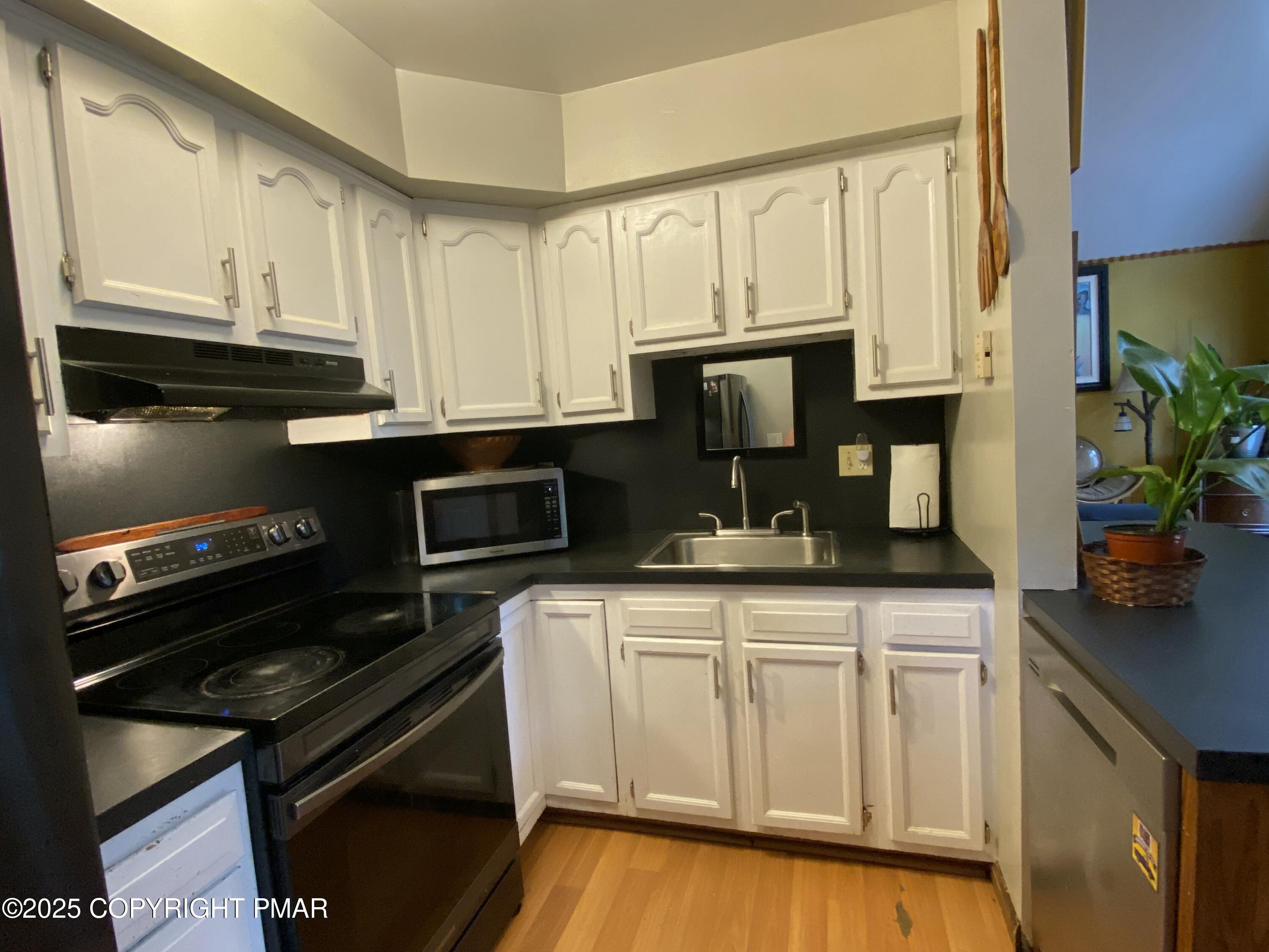 6119 Decker Road Bushkill, PA 18324 - Photo 6 of 8 a kitchen with granite countertop white cabinets and black appliances