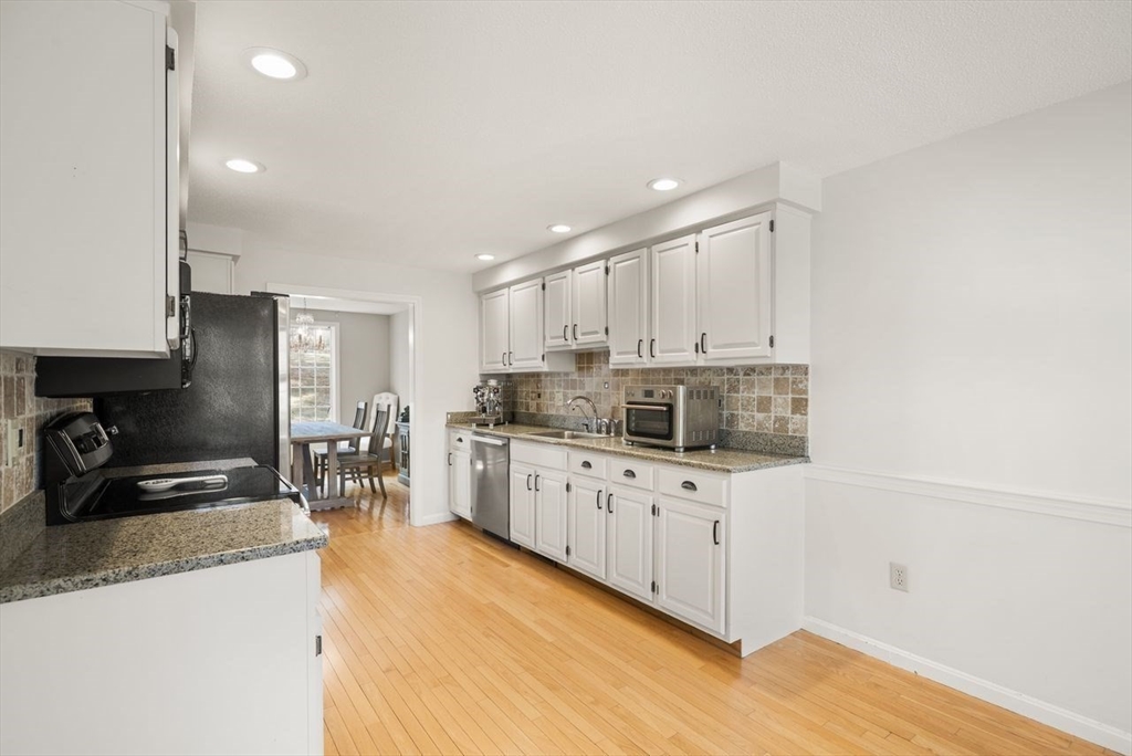 8 Bellingham Court, Unit 92 Middleton, MA 01949 - Photo 15 of 35 a kitchen with granite countertop a sink a stove top oven a counter space and cabinets