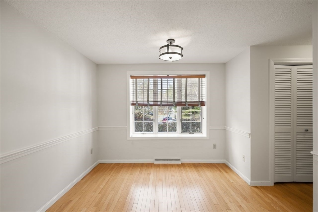 8 Bellingham Court, Unit 92 Middleton, MA 01949 - Photo 16 of 35 an empty room with wooden floor chandelier and windows