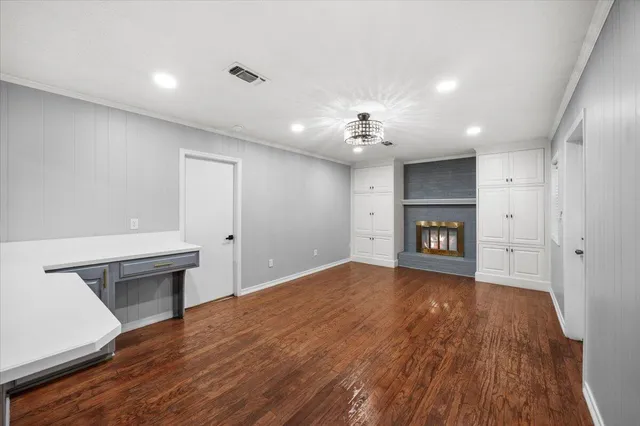 a view of a hallway with wooden floor and a kitchen