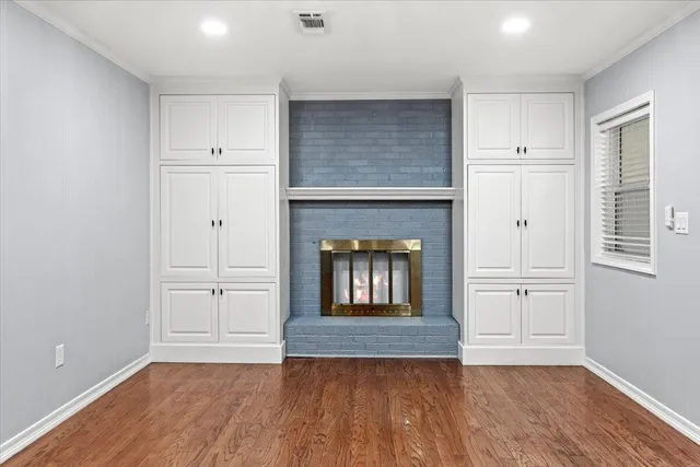 an empty room with wooden floor cabinet and front door