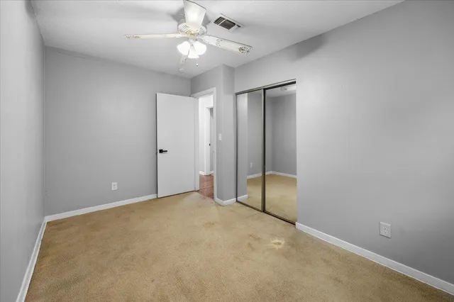an empty room with a chandelier fan and closet