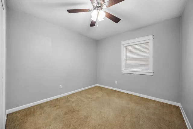 an empty room with a window and a fan
