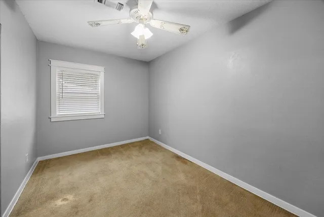 an empty room with a chandelier fan and a window