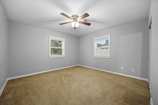 an empty room with windows and ceiling fan