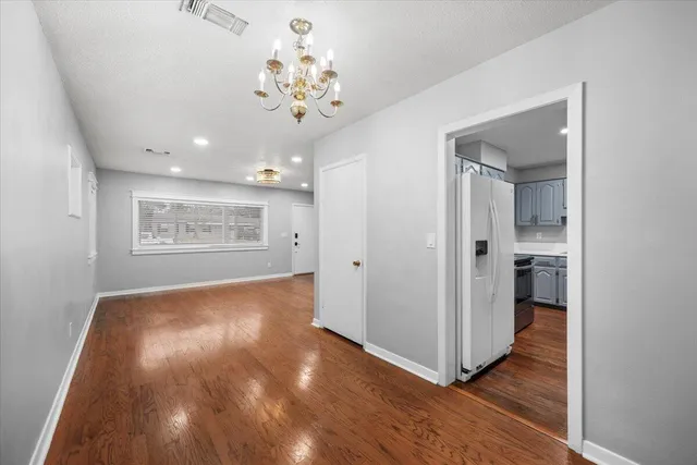 a view of a hallway with wooden floor and a kitchen
