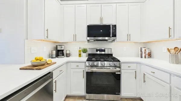 a kitchen with stainless steel appliances granite countertop white cabinets a stove a sink and dishwasher