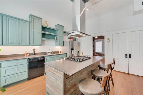 a kitchen with a stove a sink cabinets and wooden floor