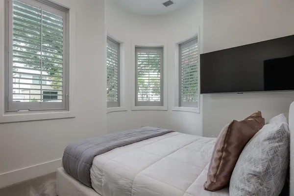 a bedroom with a bed a flat screen tv and windows