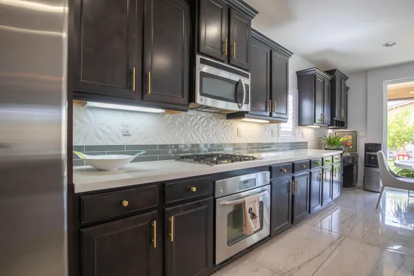 a kitchen with stainless steel appliances granite countertop a stove a sink and a microwave