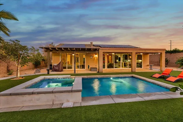 a view of swimming pool with lawn chairs and plants
