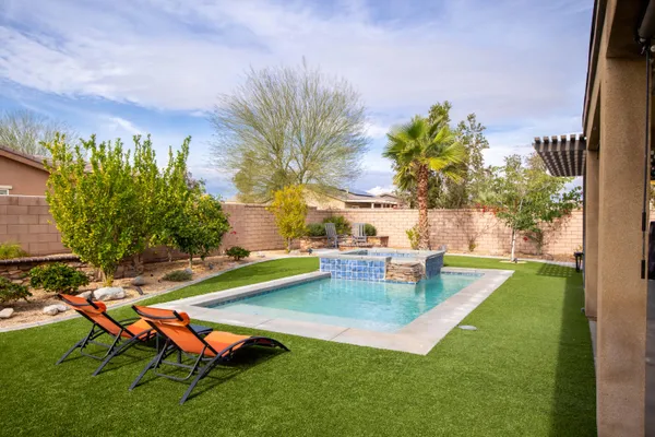 a view of a backyard with swimming pool and sitting area