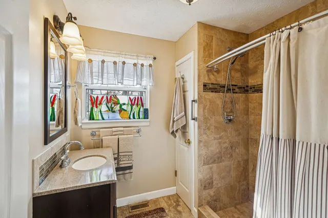 a bathroom with a sink vanity granite and a shower