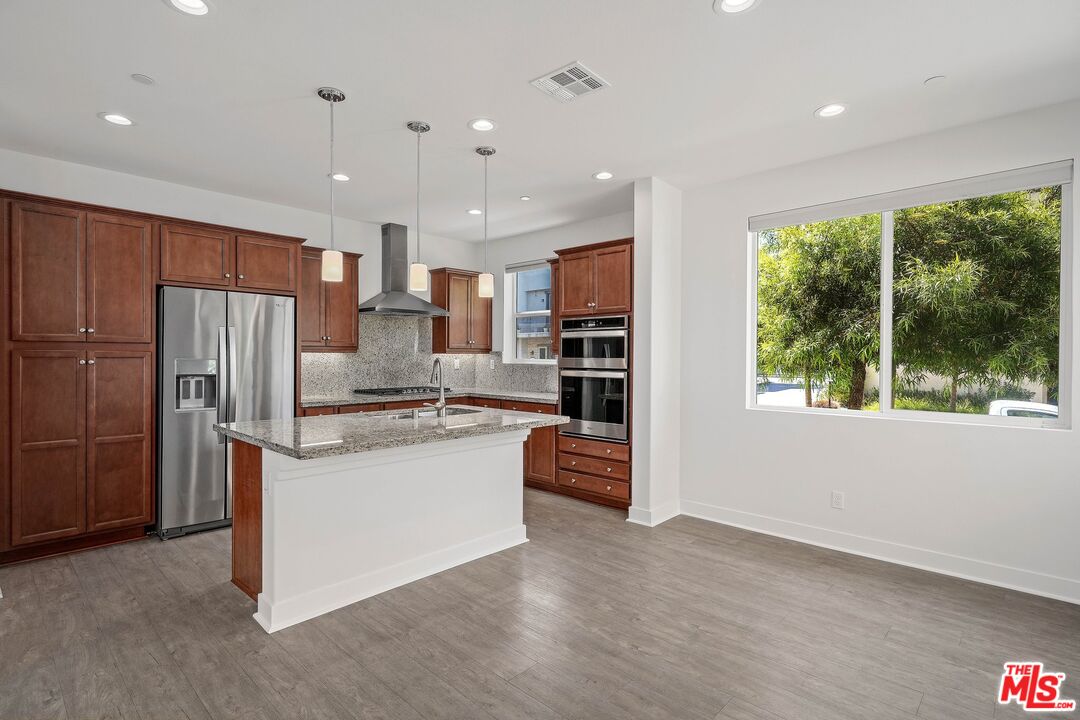 659 Daniel Freeman Circle Inglewood, CA 90301 - Photo 8 of 34 a kitchen with stainless steel appliances granite countertop a refrigerator a sink dishwasher a stove and a refrigerator with wooden floor