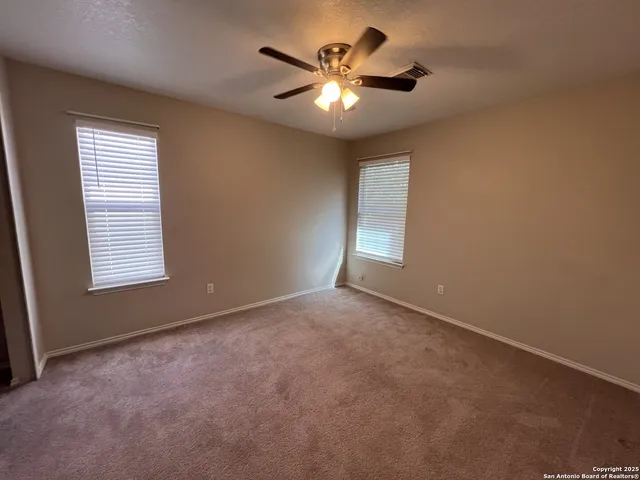 an empty room with windows and fan