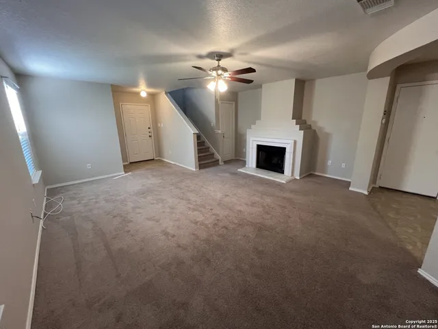 a view of a livingroom with a ceiling fan a fireplace and entryway