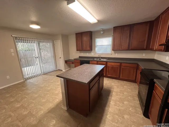 a kitchen with stainless steel appliances granite countertop a stove a sink dishwasher and a refrigerator with wooden cabinets