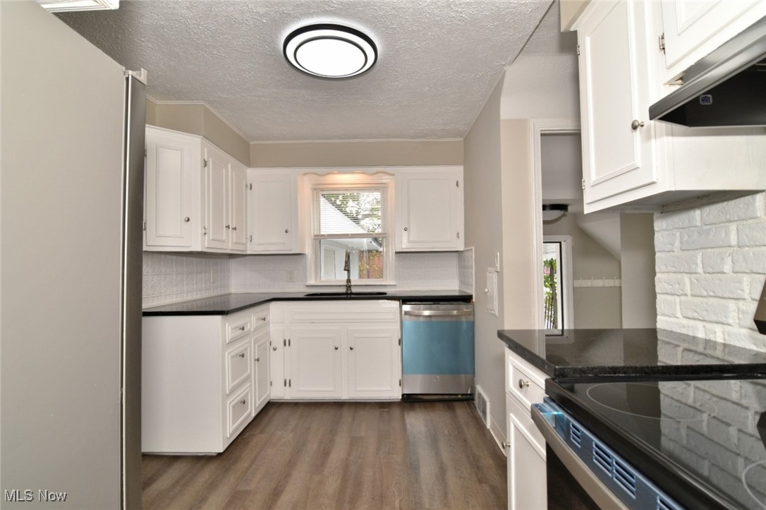 1443 Churchill Road Lyndhurst, OH 44124 - Photo 22 of 39 Kitchen featuring stainless steel appliances, dark wood-type flooring, under cabinet range hood, a textured ceiling, and white cabinetry
