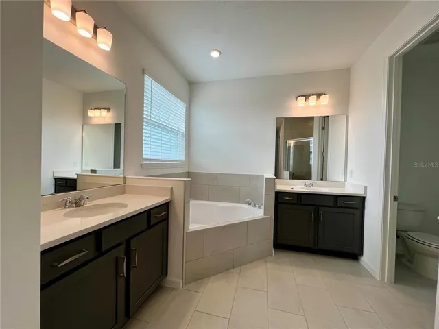 a spacious bathroom with a tub sink and mirror