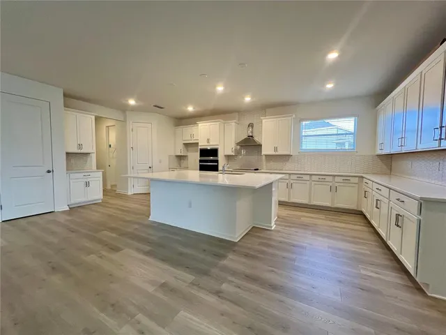 a large kitchen with stainless steel appliances kitchen island a large counter top and a stove top oven