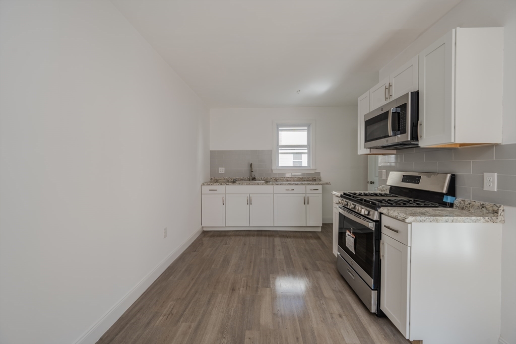 348 Walker Street Lowell, MA 01851 - Photo 18 of 20 a kitchen with cabinets wooden floor and stainless steel appliances