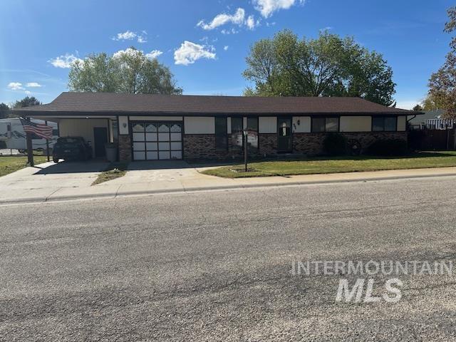 Single story home featuring an attached carport, concrete driveway, a front lawn, and brick siding