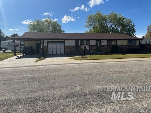 601 Riggs Avenue Emmett, ID 83617 - Photo 10 of 46 Ranch-style house with an attached carport, concrete driveway, brick siding, and a front lawn