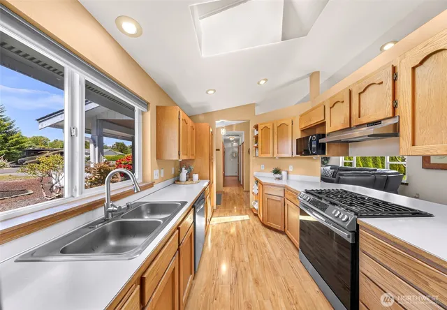 a kitchen with stainless steel appliances granite countertop a sink a stove and a wooden floors