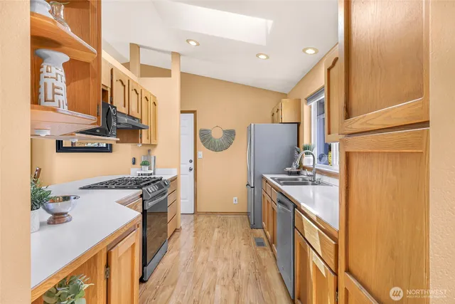 a kitchen with stainless steel appliances granite countertop hardwood floor sink stove and refrigerator