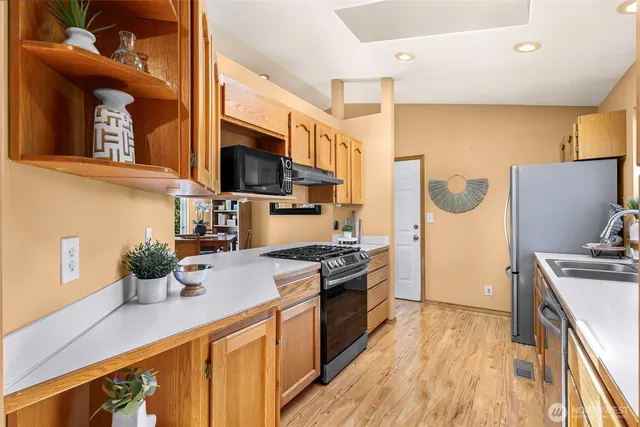 a kitchen with stainless steel appliances a stove refrigerator sink and wooden floor