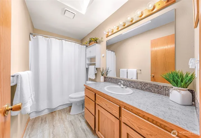 a bathroom with a granite countertop sink a toilet and a mirror