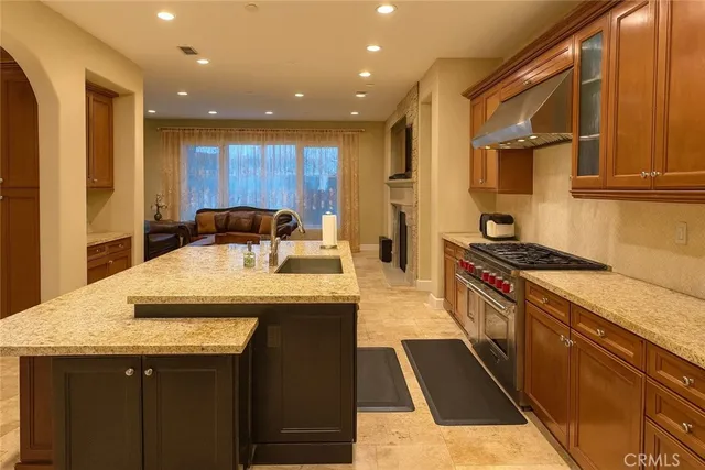 a kitchen with kitchen island granite countertop a sink and a stove top oven with wooden floor