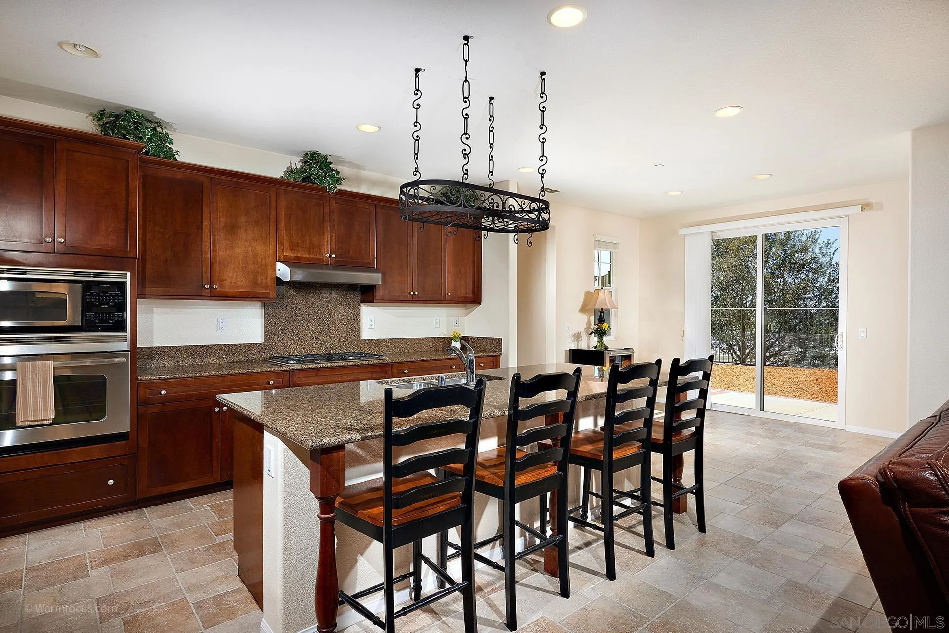 3025 Calico Street Santee, CA 92071 - Photo 14 of 59 a kitchen with stainless steel appliances granite countertop a stove a sink dishwasher a dining table and chairs with wooden floor