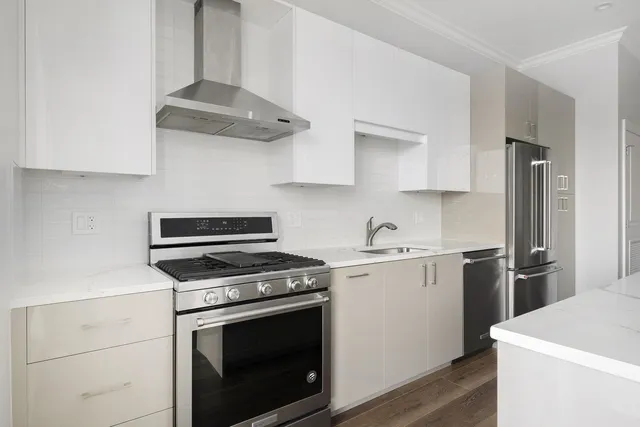 a kitchen with cabinets stainless steel appliances and a wooden floor