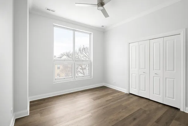 an empty room with wooden floor fan and windows